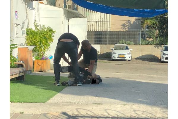 בתמונה שוטרים עוצרים את החשוד